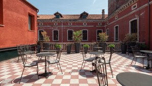 Une cour avec un sol à carreaux, des sièges en plein air et des plantes en pot.