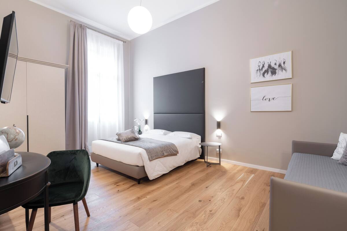 A modern bedroom with a bed, bedside table, chair, and artwork on the wall.
