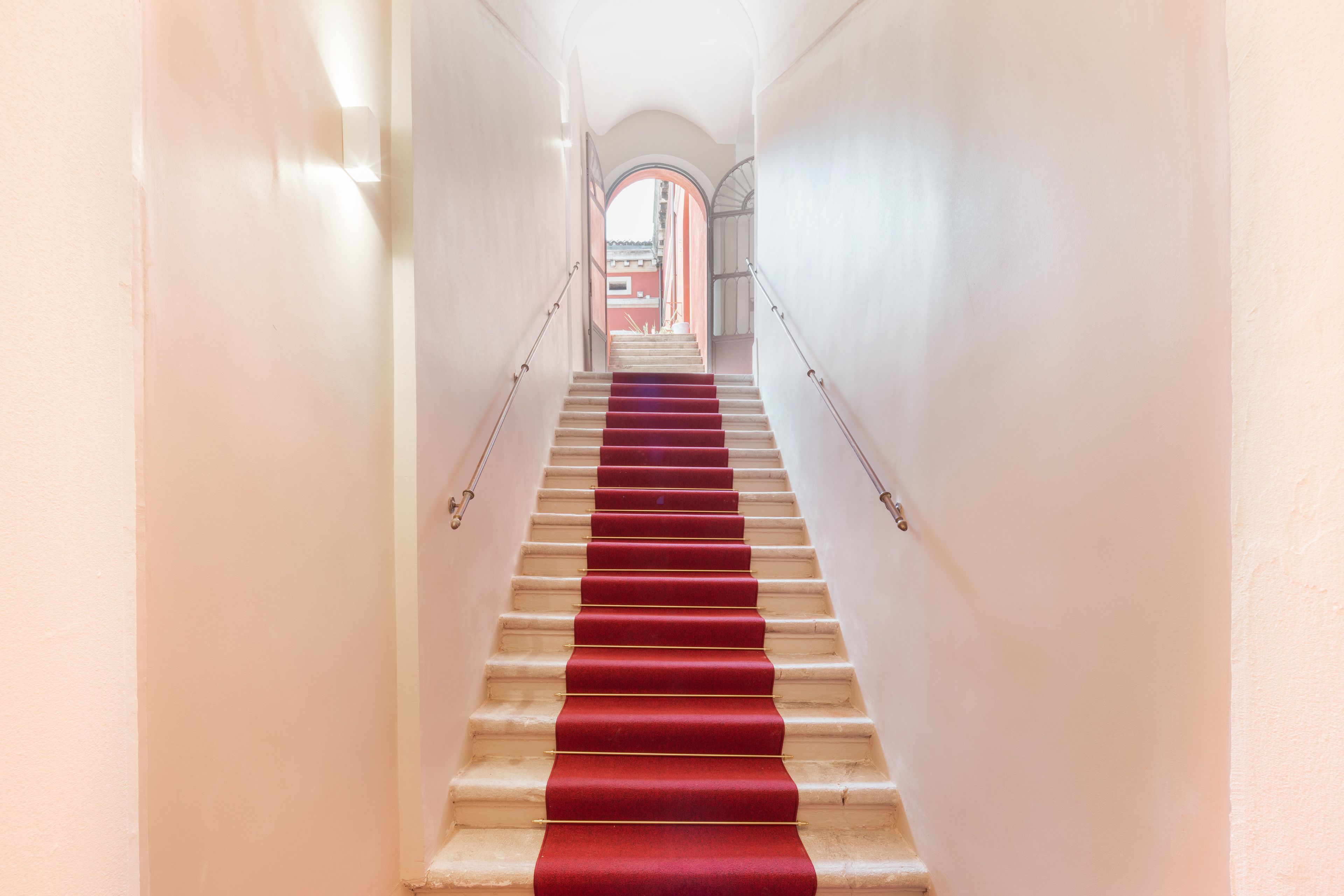 A staircase with red carpeted steps and white walls.