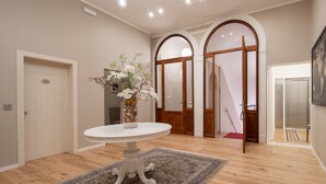 Un couloir avec une table ronde, un vase de fleurs et un tapis à motifs.