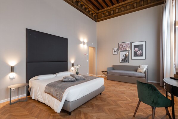 A modern bedroom with a large bed, a sofa, and a desk.