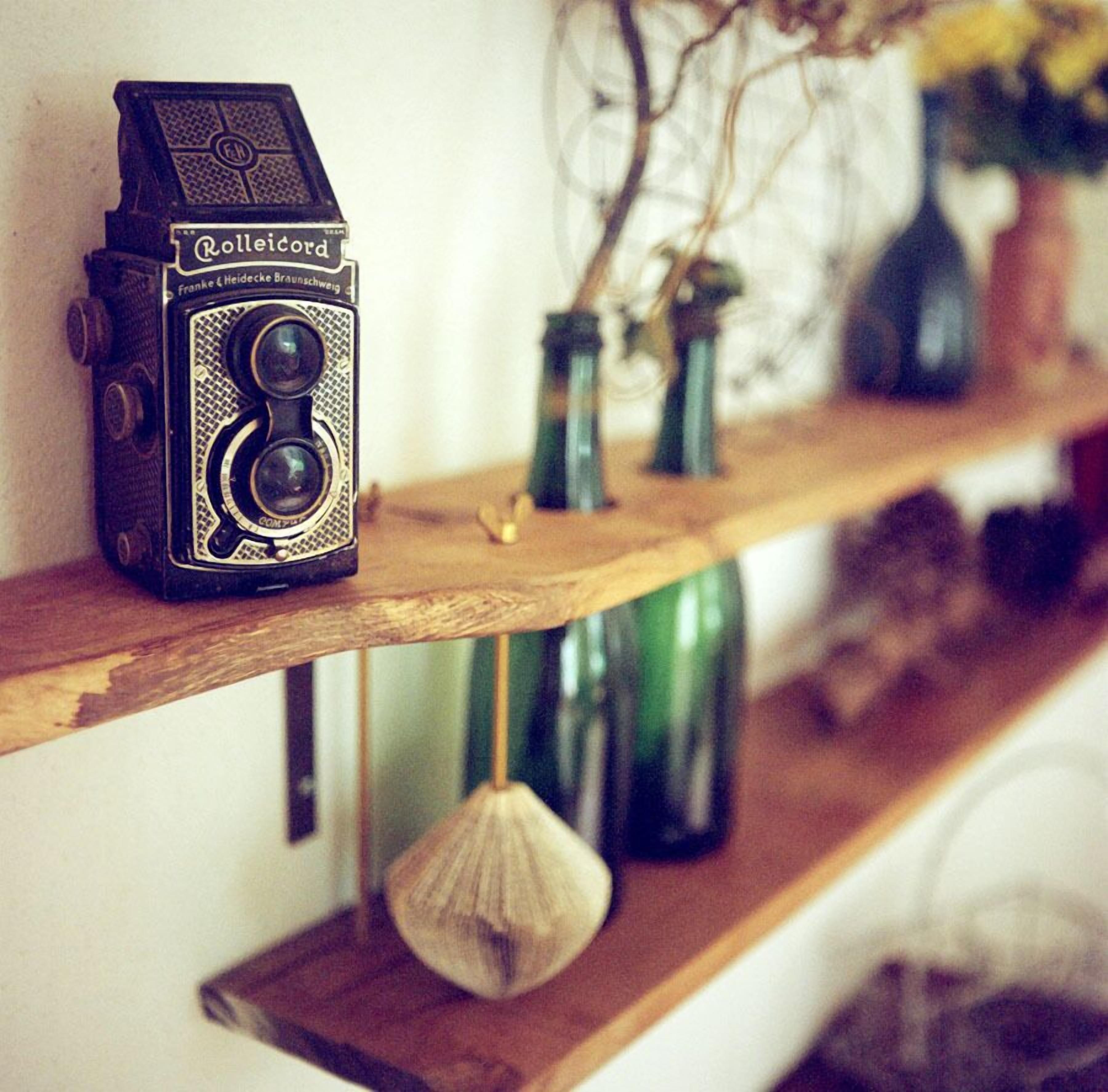 Un appareil photo Rolleicord vintage, posé sur une étagère en bois.