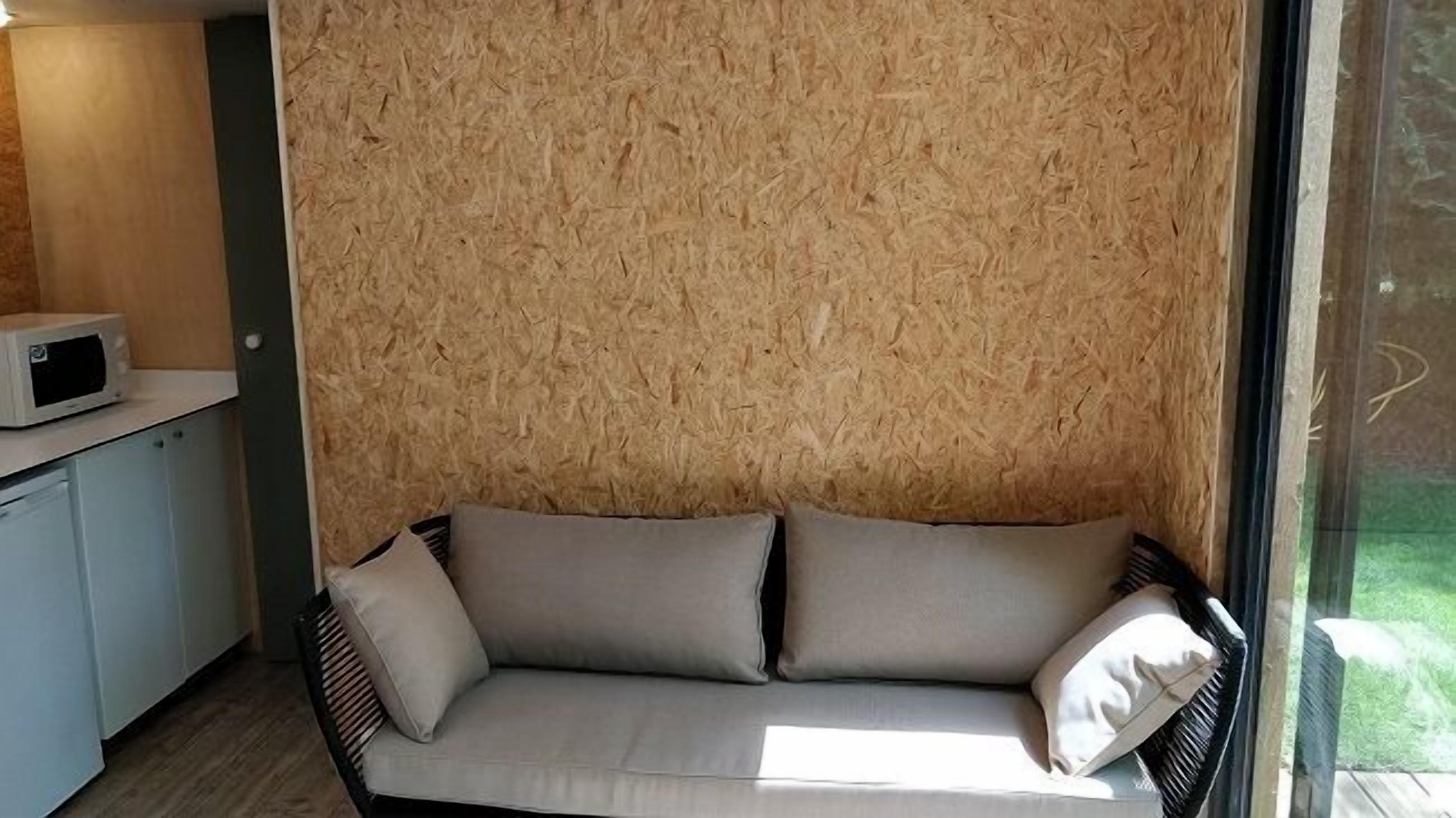 Un espace de vie moderne avec un mur en bois, un canapé blanc agrémenté de coussins et un four à micro-ondes posé sur un comptoir.