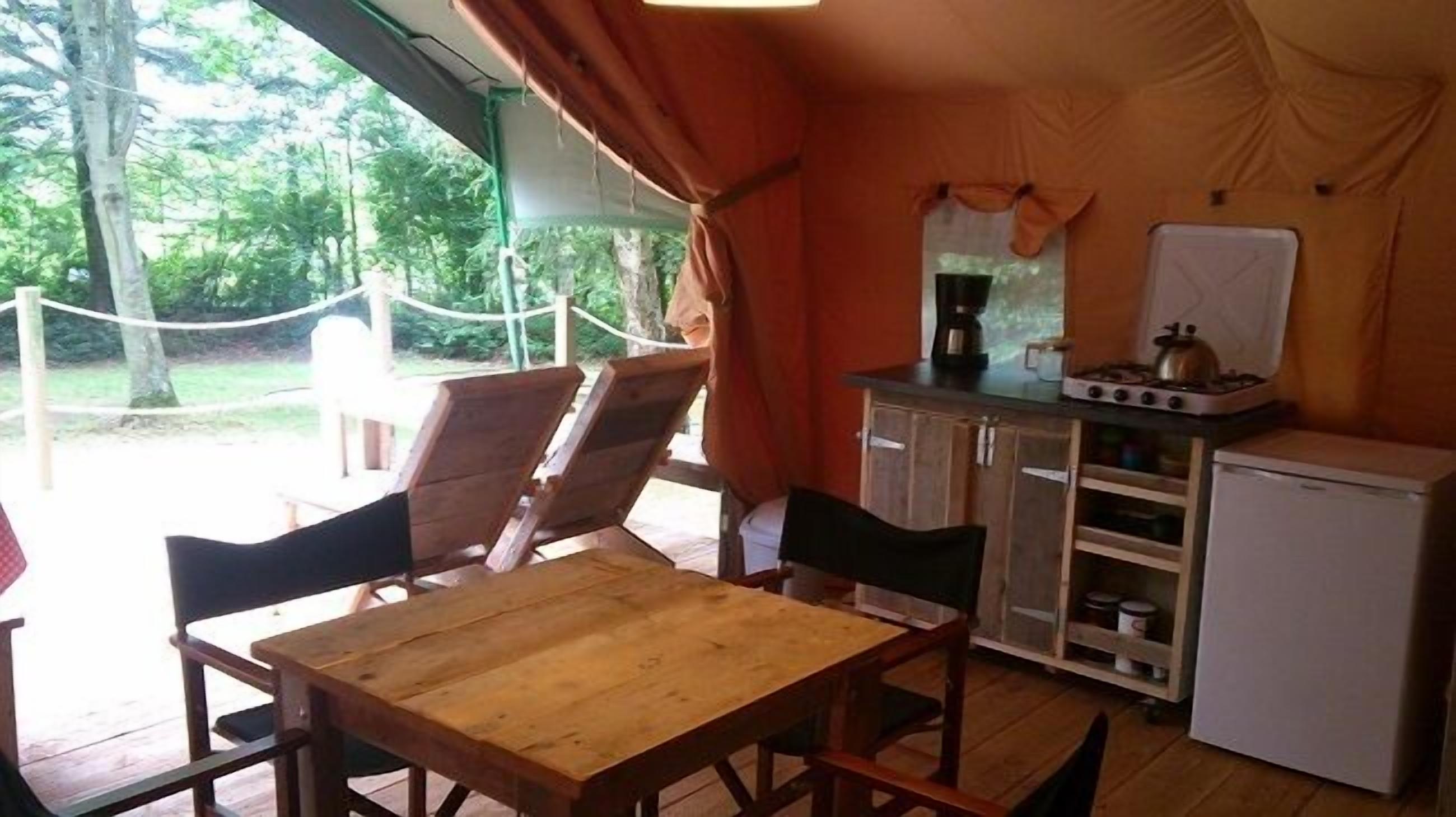 Una pequeña cocina con una mesa, sillas, un refrigerador y una estufa.