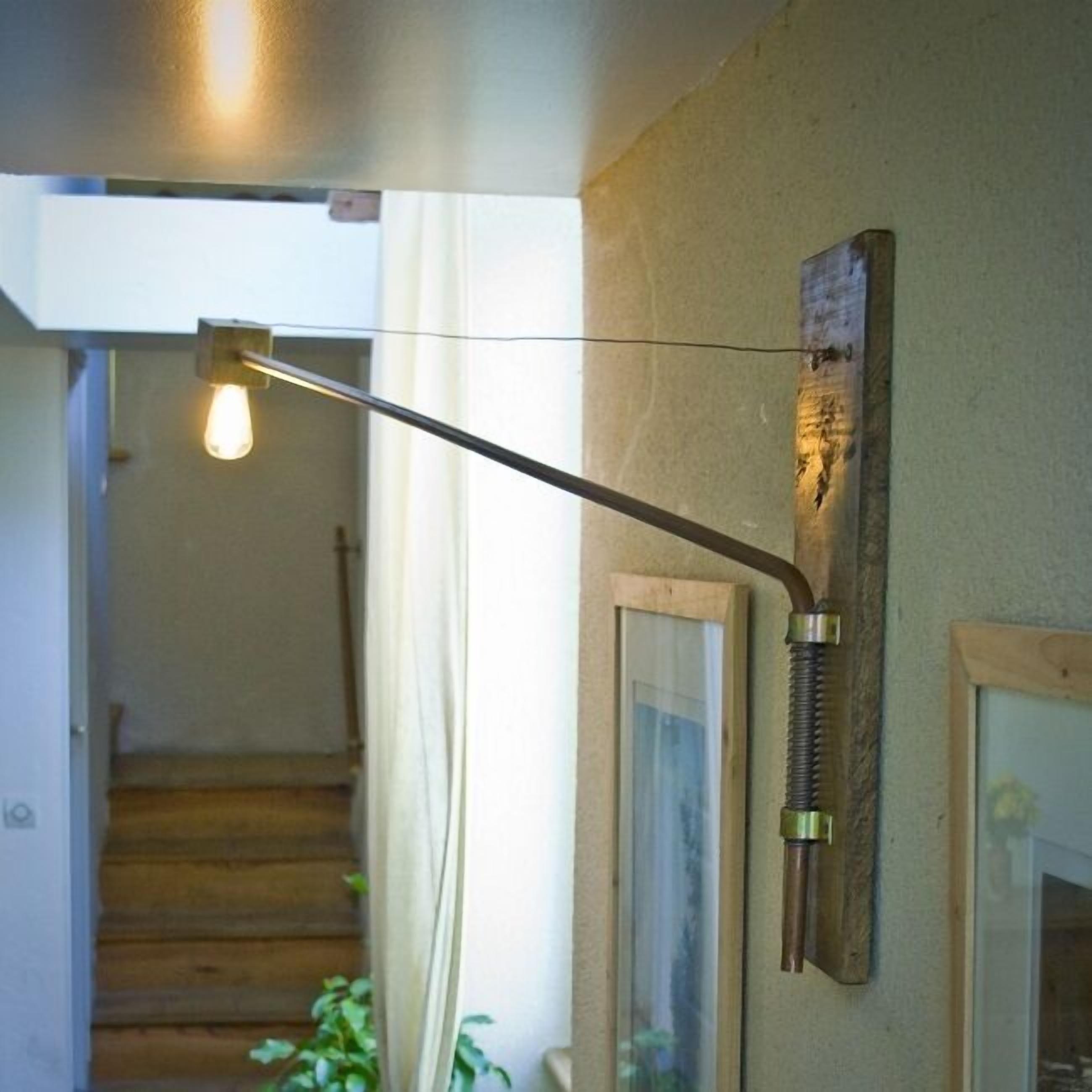 A hallway with a wooden staircase, a wall-mounted light fixture, and a framed picture.