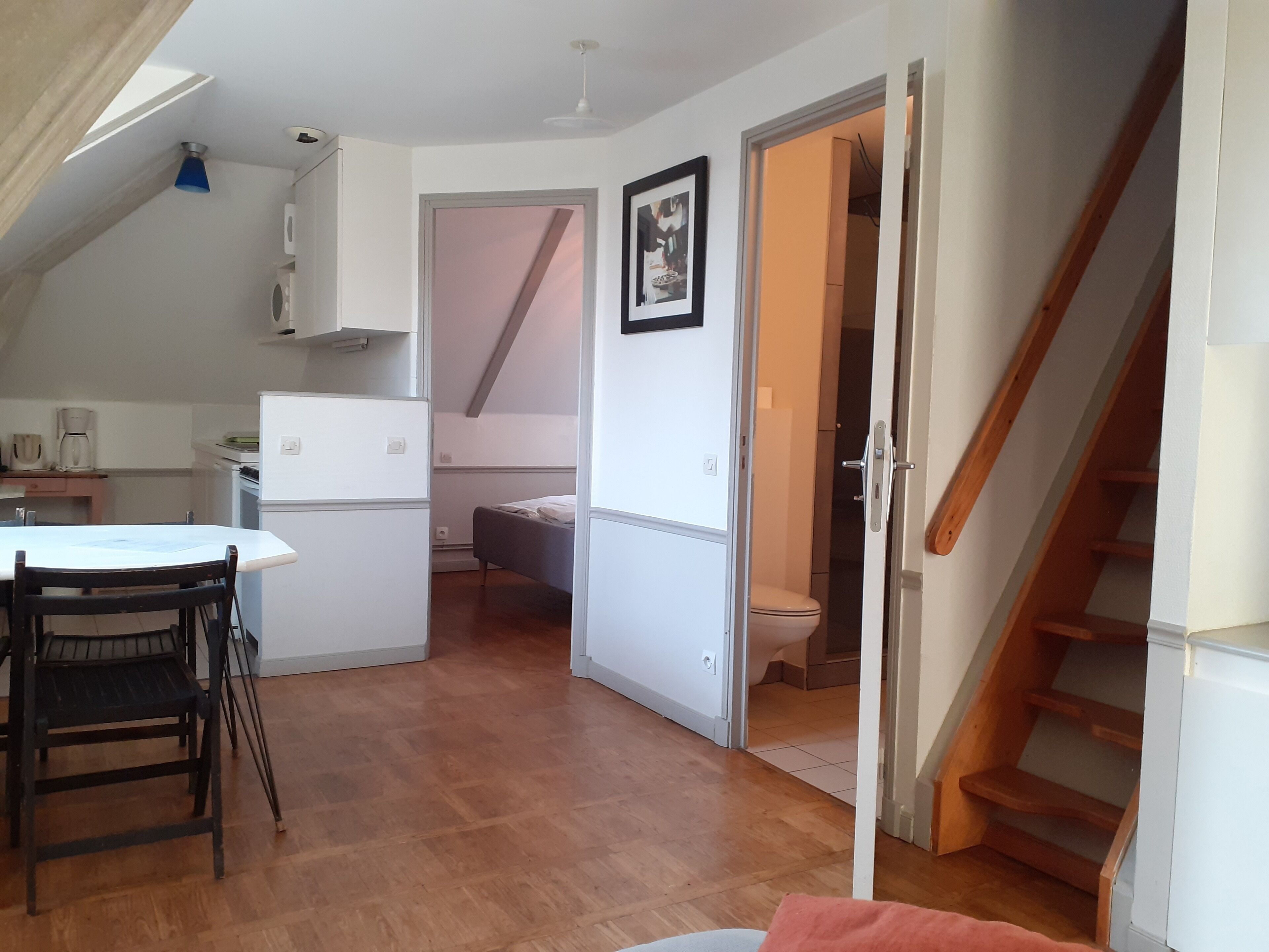 Un espace de vie compact comprenant un coin cuisine, un coin repas et une chambre.