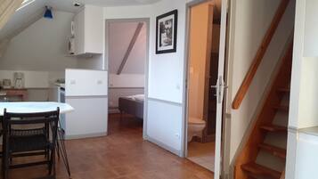 Un espace de vie compact comprenant un coin cuisine, un coin repas et une chambre.
