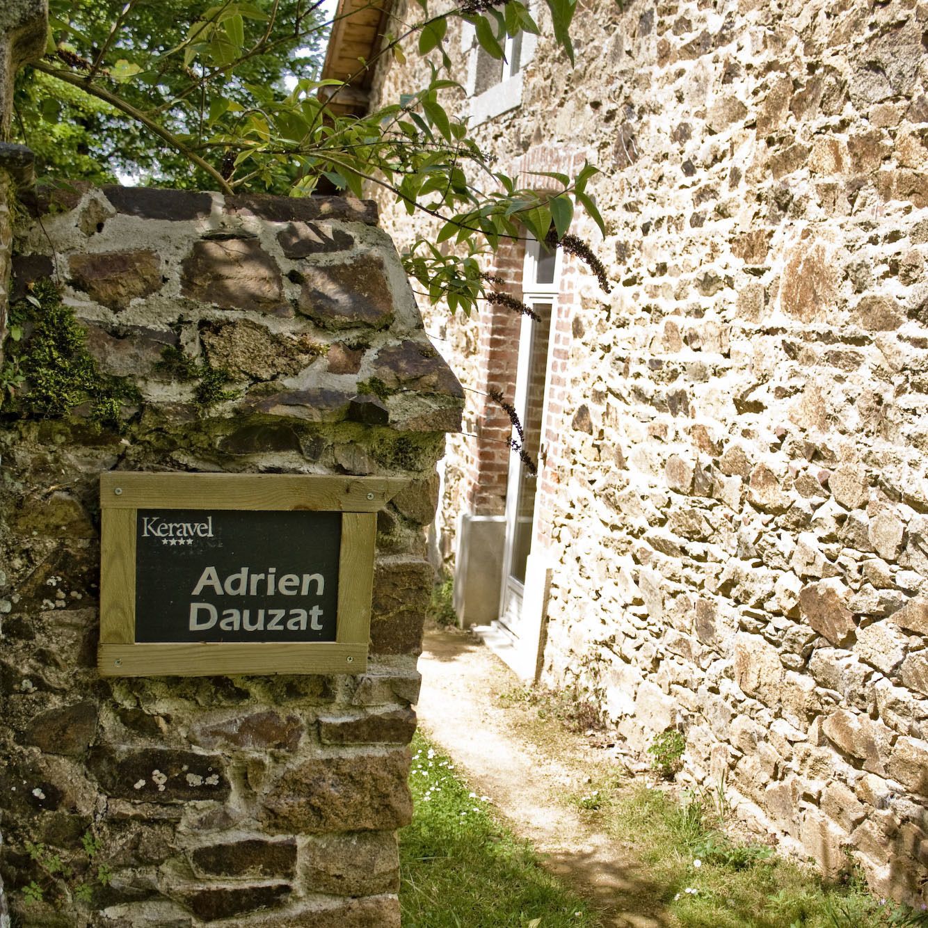 Un mur de pierres sur lequel est apposée une plaque portant l’inscription « Keravel Adrien Dauzat ».
