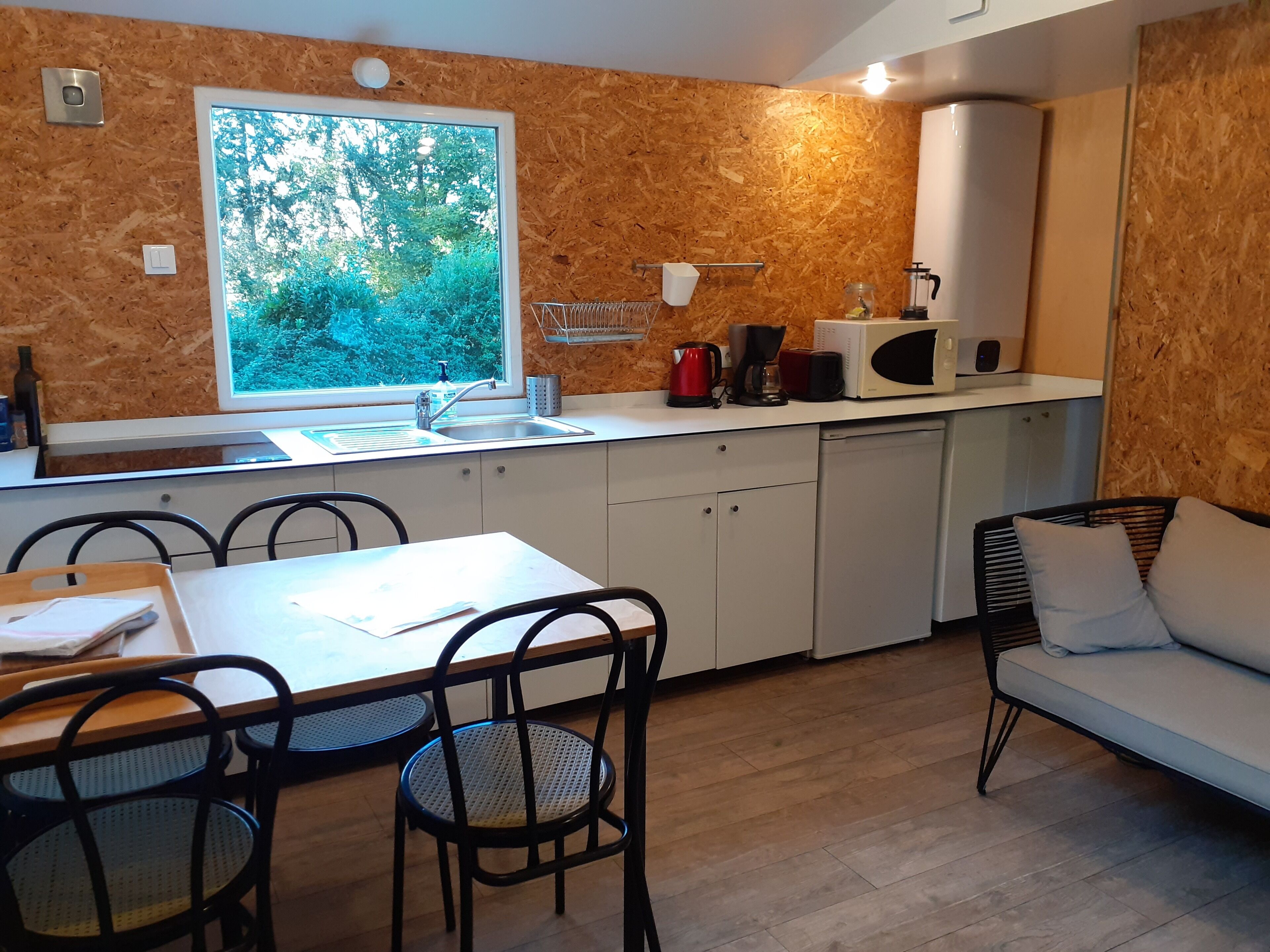 Cocina compacta con ventana, pileta y electrodomésticos básicos. Cuenta con un comedor con mesa y sillas.