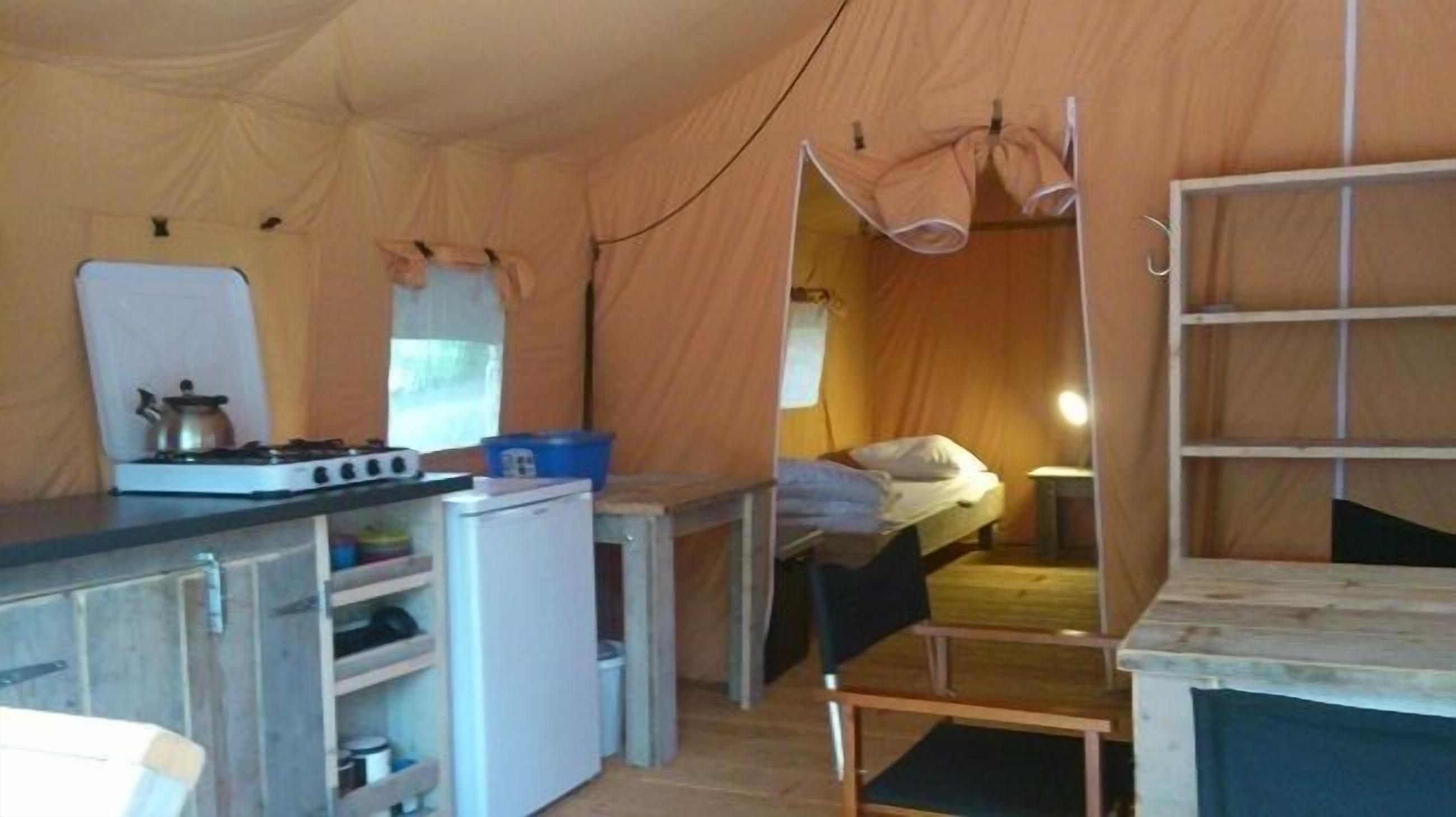 A compact tent with a kitchenette, a bed, and a small table.
