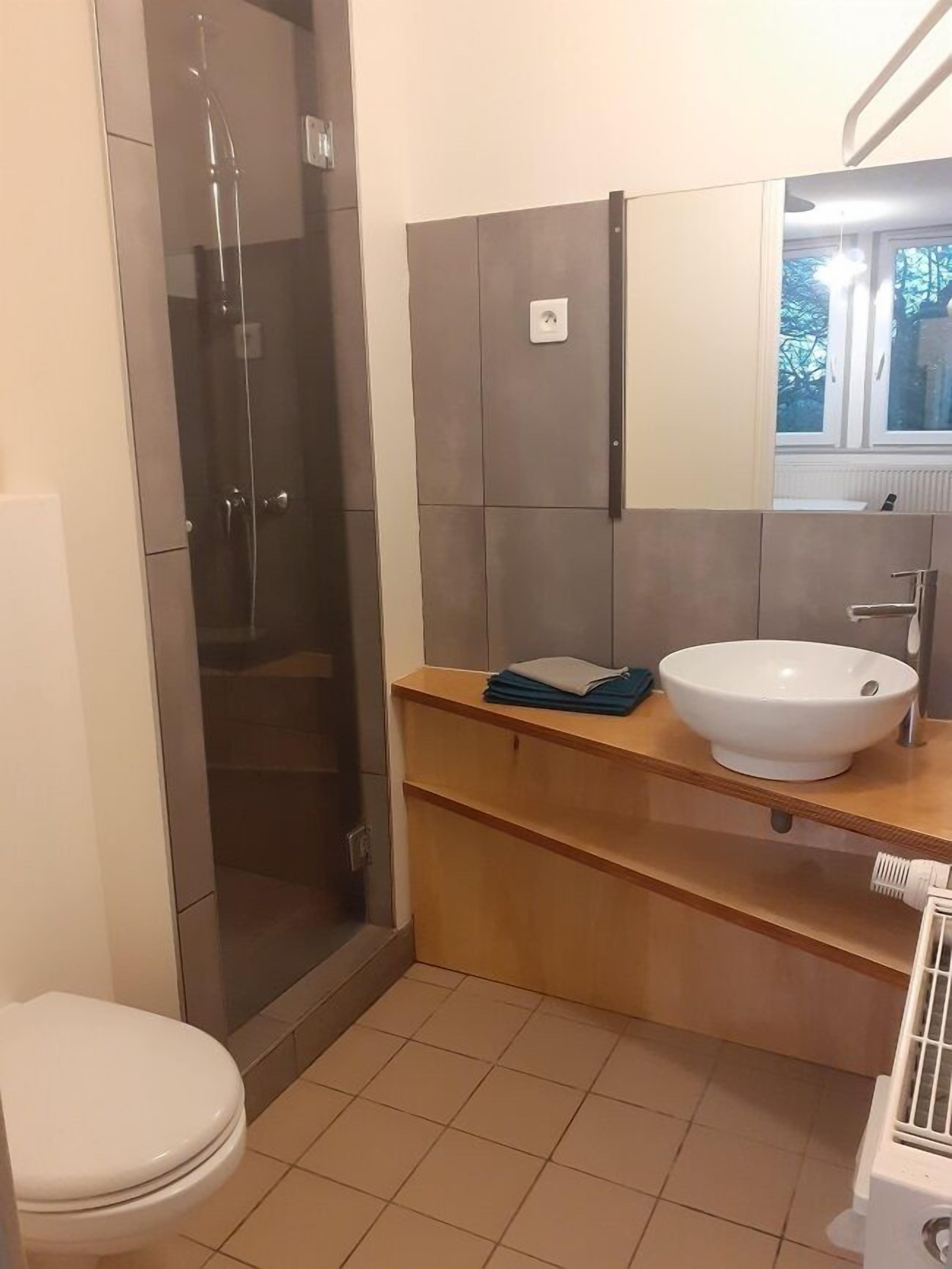 Une salle de bain avec une douche à parois de verre, un lavabo blanc et un miroir au-dessus du lavabo.