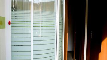 A glass-enclosed shower area with a green mat, a visible showerhead, and a tiled floor.
