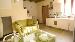 A compact kitchen with a dining area, featuring a green table set with plates, a bottle, and candles. - Camera 40 - In Gorgonzola (Gorgonzola)