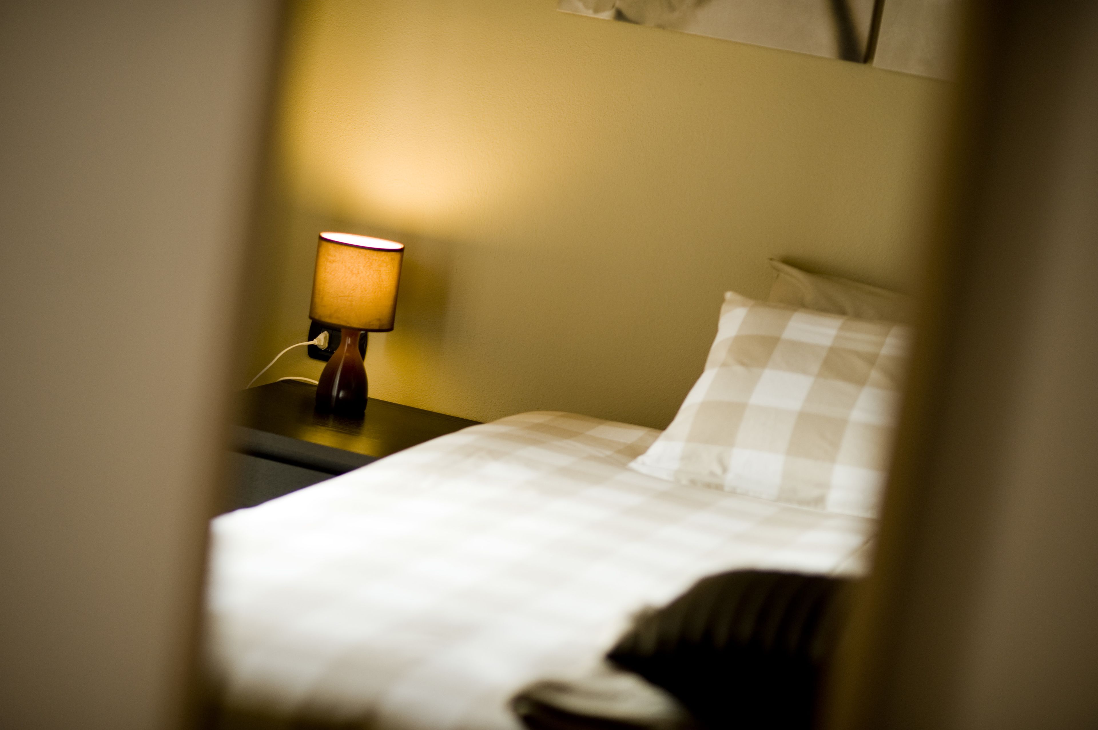 Een hotelkamer met een bed, nachtkastje en een lamp.