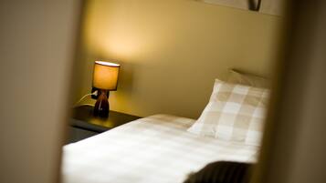 Een hotelkamer met een bed, nachtkastje en een lamp.
