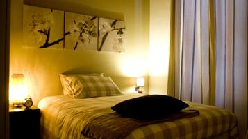 Ein Schlafzimmer mit einem Bett, zwei Nachttischen mit Lampen, einer Wanduhr und einem Fenster mit Vorhängen.