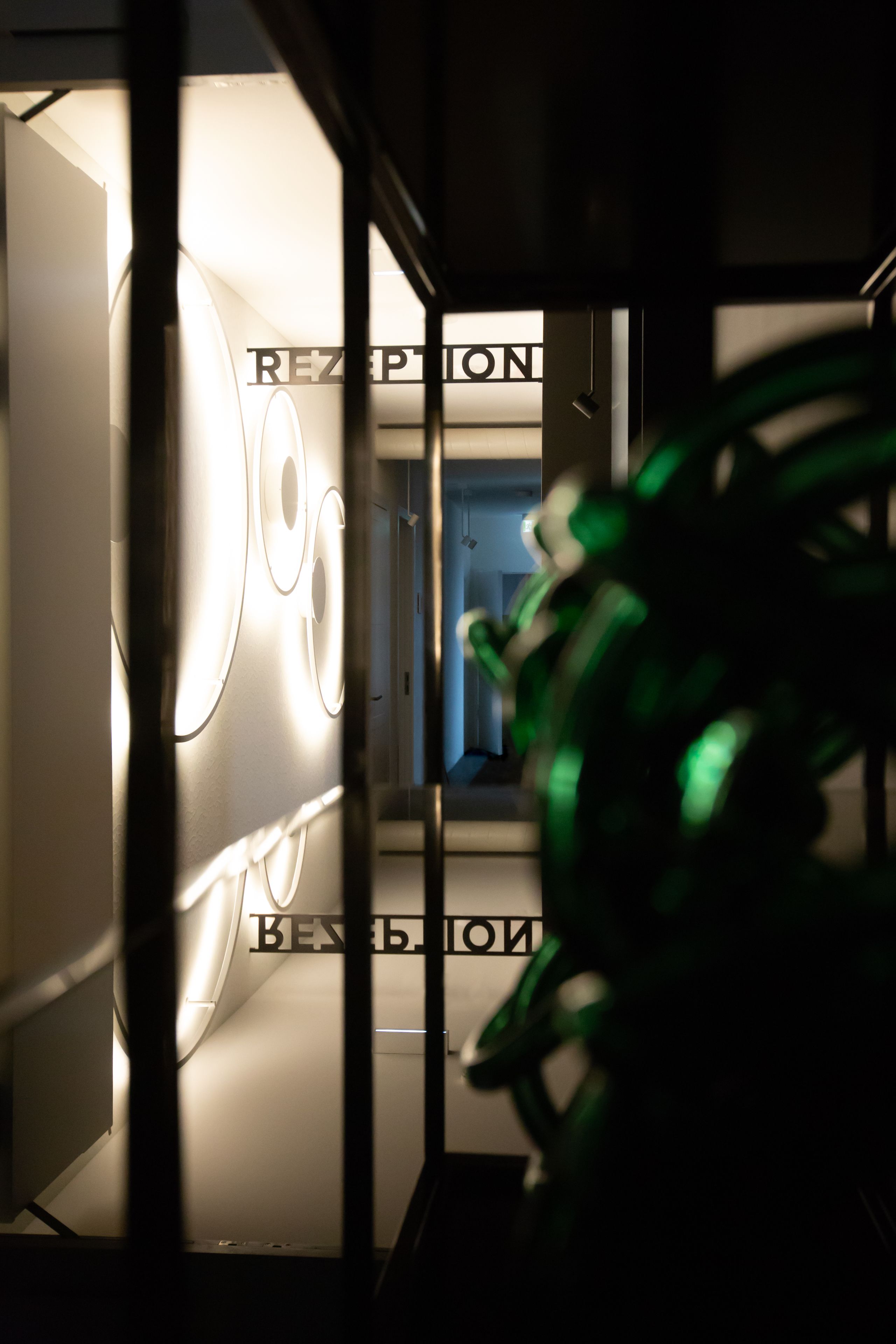 Een receptiezone met een modern ontwerp, met verlichte signalisatie en een groene decoratie.
