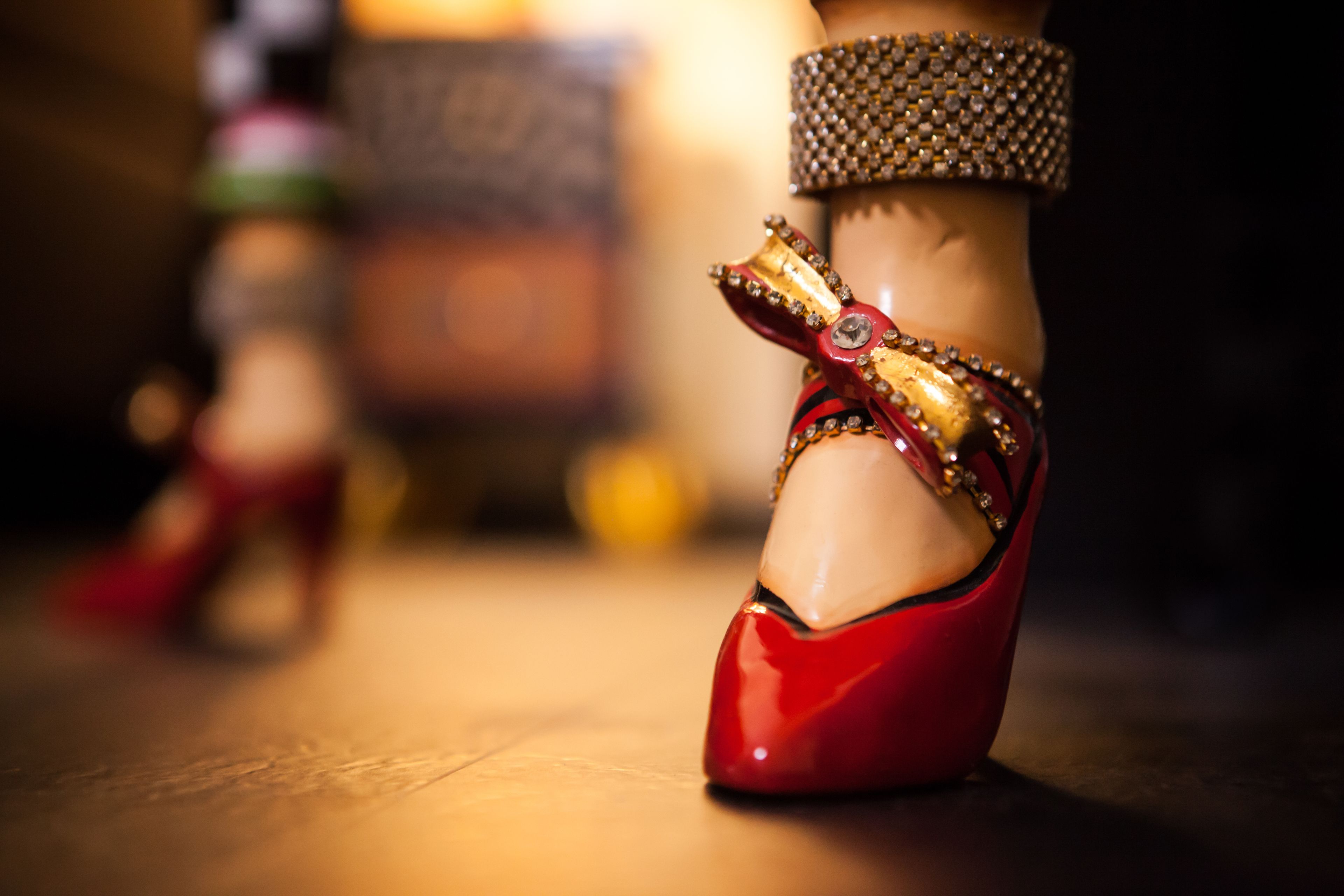 Primer plano de un zapato tacón rojo con un lazo decorativo y correa para tobillo.