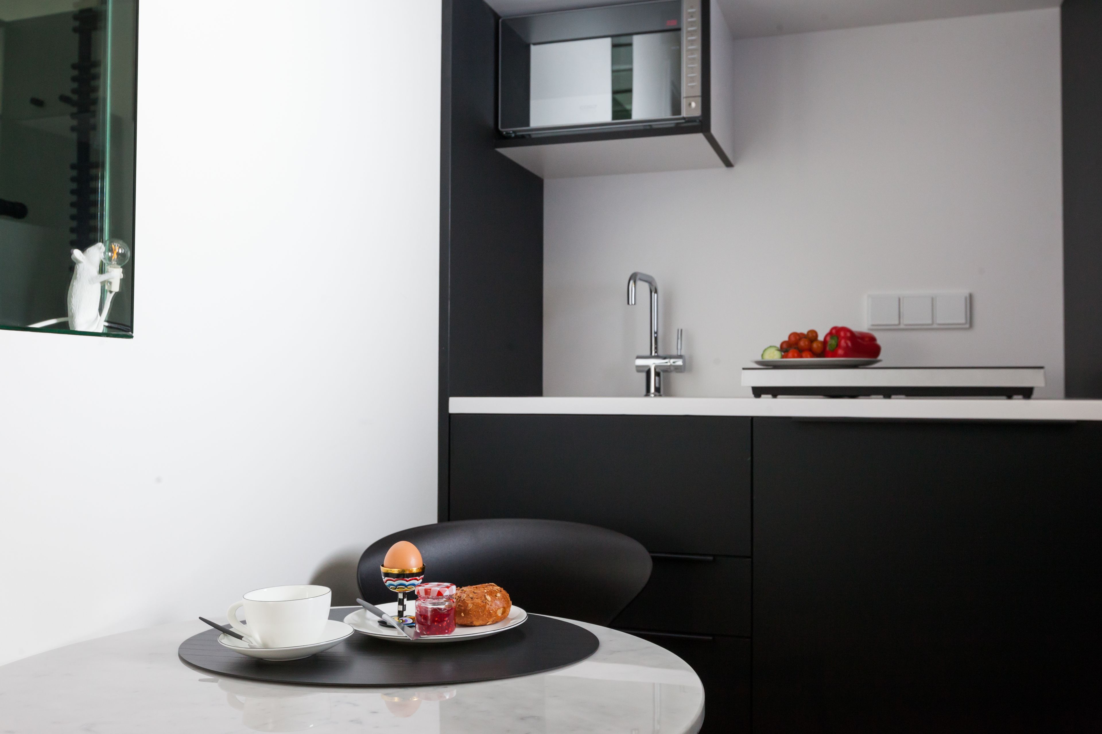 A modern kitchen with a built-in microwave, a sink, and a countertop with a bowl of fruit.