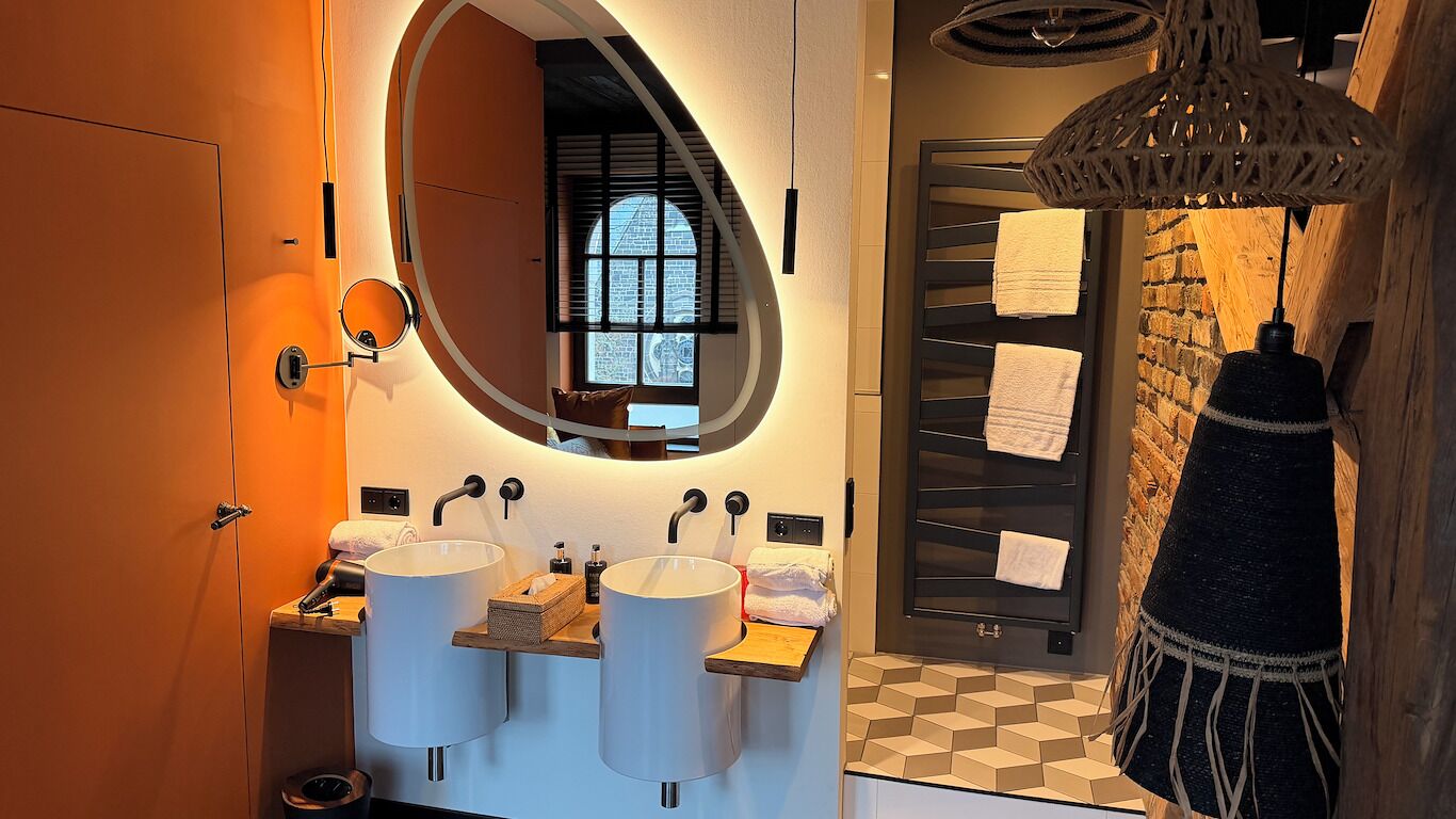 Un bagno con due lavandini, uno specchio, una finestra, un portascopevoli e una lampada a sospensione.