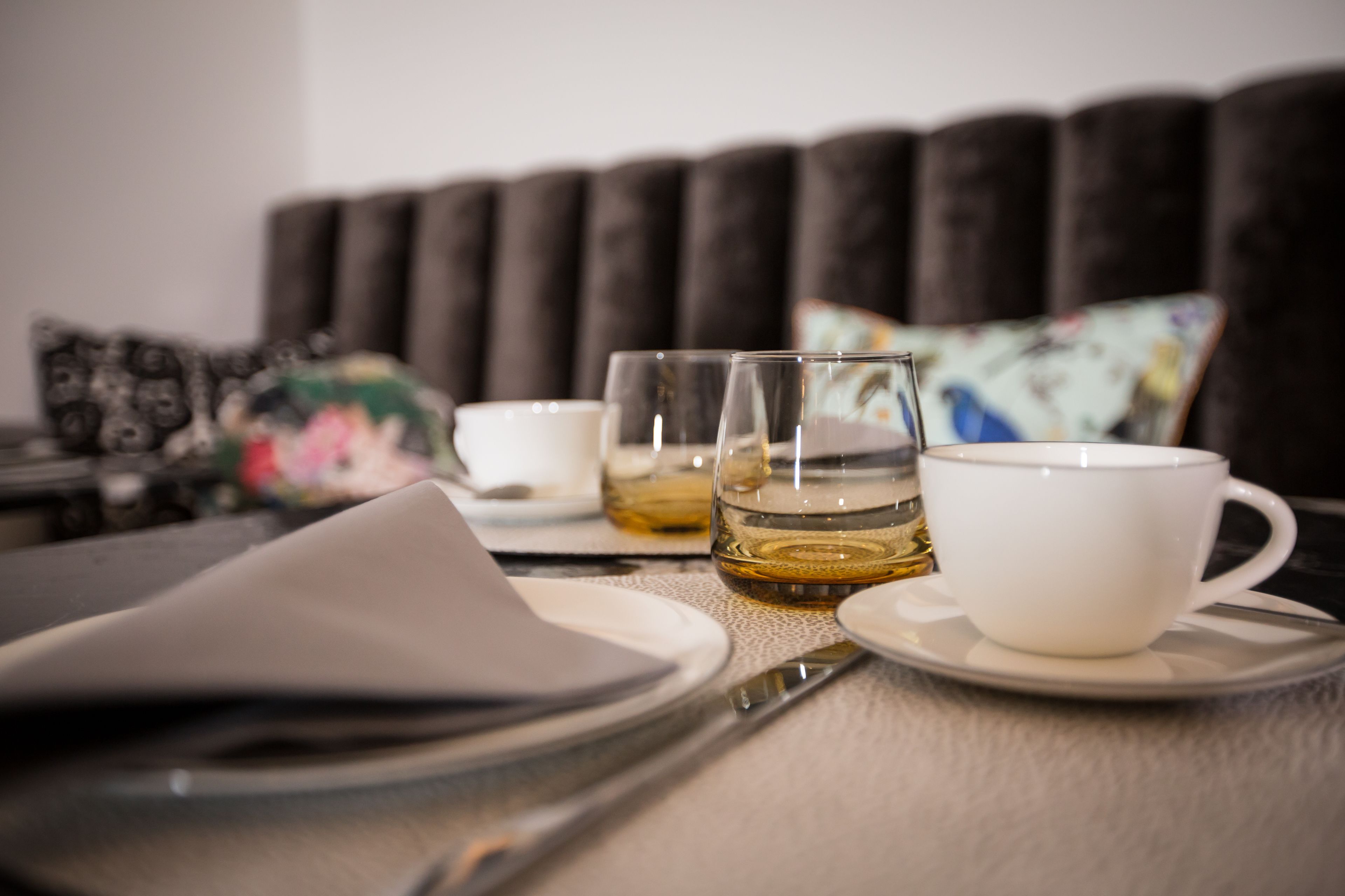 A table set with a white cup, a glass of amber liquid, and a folded napkin.