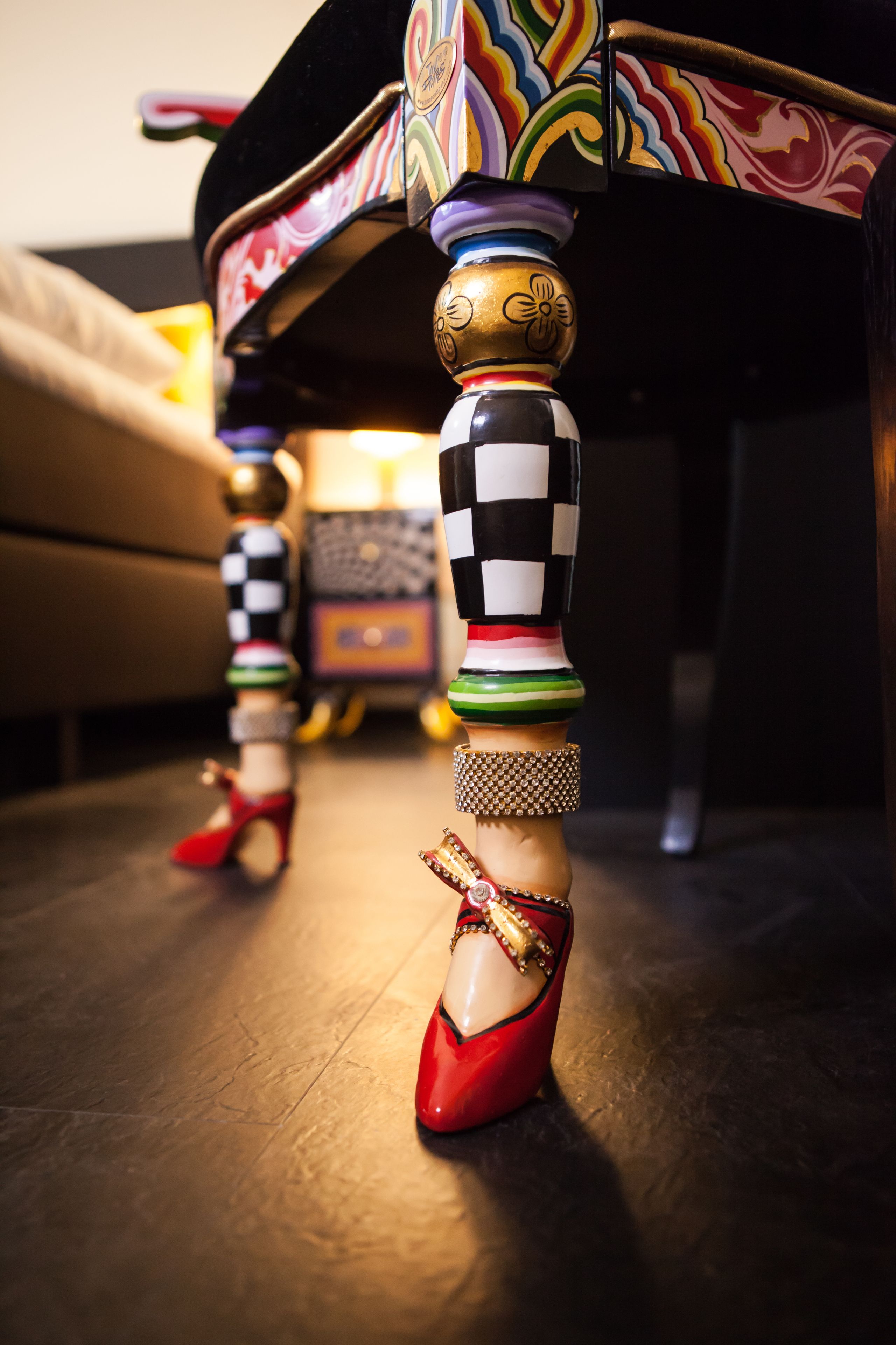 Primer plano de una figura decorativa de madera con estampado de cuadros y un zapato rojo.