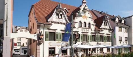 Un edificio histórico con un estilo arquitectónico europeo tradicional, que presenta una entrada destacada con un balcón y una torre del reloj.
