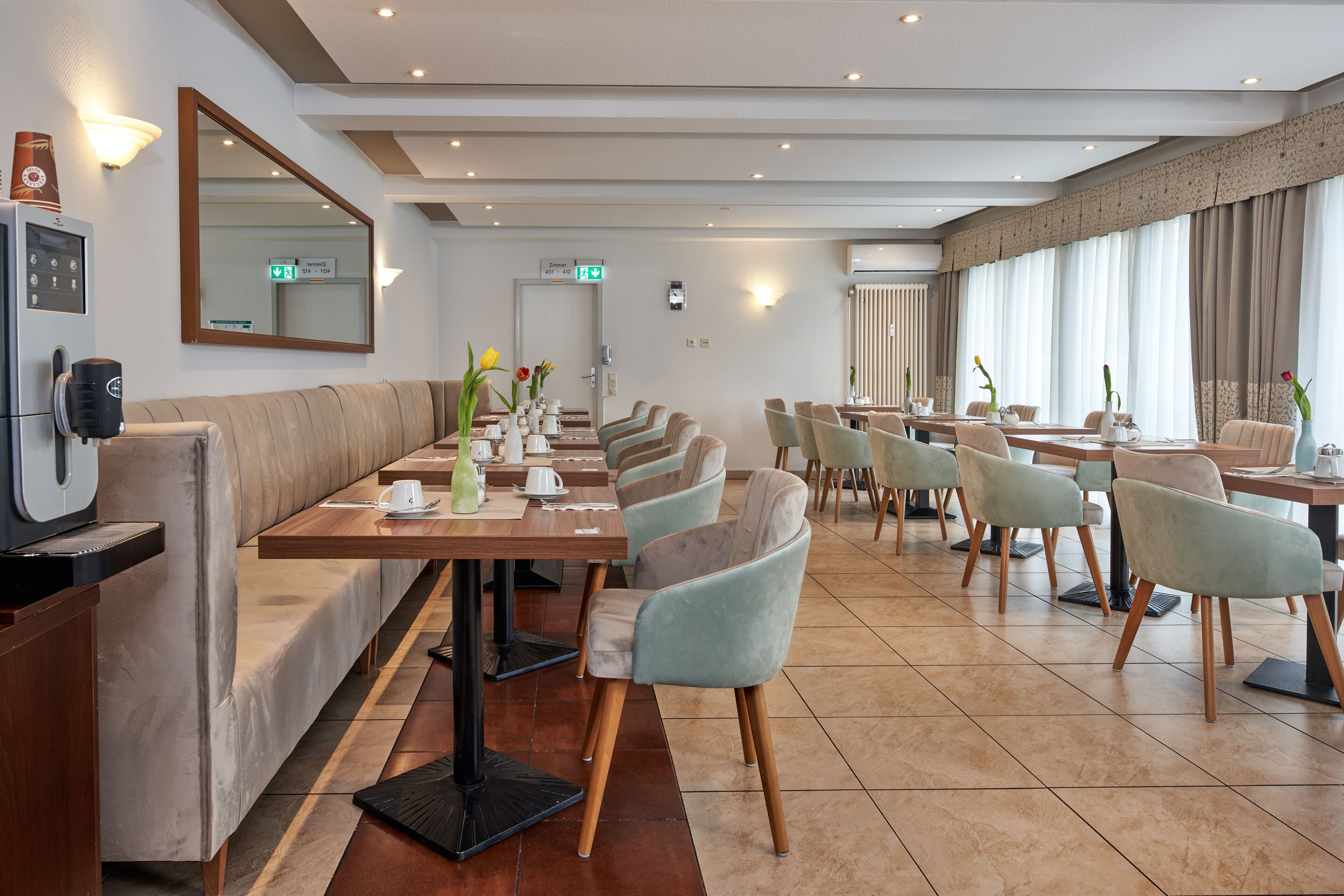 Un restaurante moderno con una barra alargada, asientos acolchados y un espejo grande.