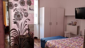 A bedroom with a bed, a dresser, a vanity, and a TV. - Smiling Naples (Naples)