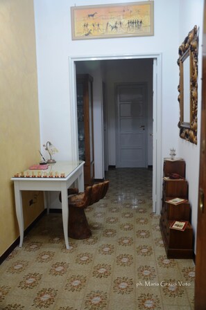 A hallway with a white door, a table with a lamp, and a mirror on the right. - Smiling Naples (Naples)