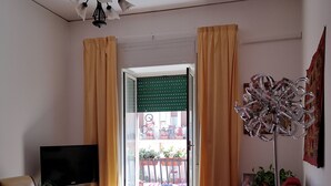 A living room with a wooden floor, a red sofa, a rocking chair, a TV, and a floor lamp. - Smiling Naples (Naples)