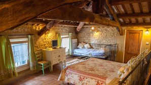 A rustic bedroom with a stone wall, a bed with floral bedding, a desk with a computer, and a chair. - Country Club Da Cesco (Borso del Grappa)