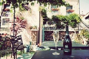 A table with a bottle of wine and a glass of wine, set outdoors with a view of a stone building and greenery. - Country Club Da Cesco (Borso del Grappa)