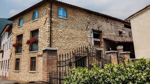 A stone building with multiple windows, a metal gate, and a staircase leading to a balcony. - Country Club Da Cesco (Borso del Grappa)