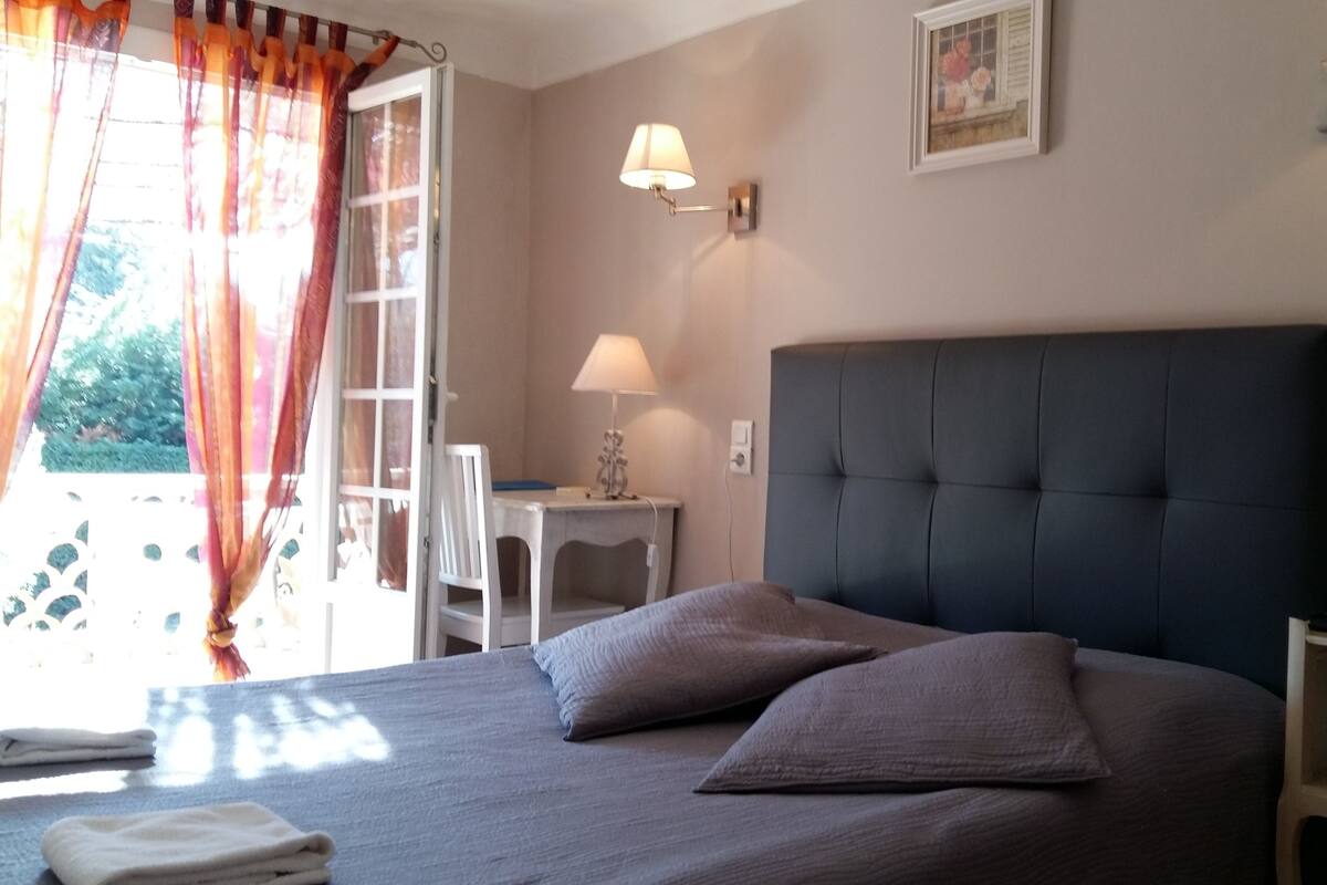 A bedroom with a large bed, two pillows, a nightstand, a lamp, and a picture on the wall.