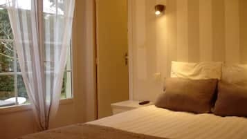 Un dormitorio con cama, mesita de noche, cortinas y una puerta.