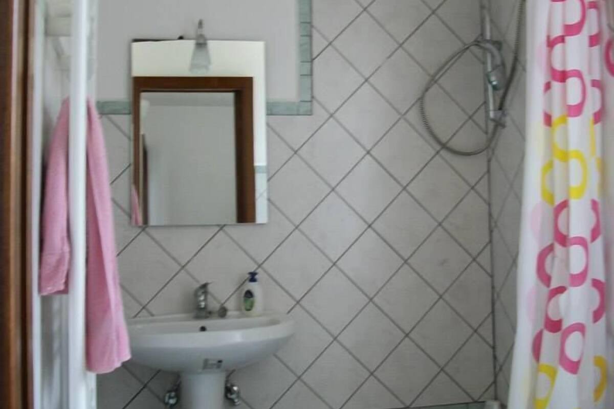 Un baño con lavamanos, espejo, ducha y cortina de ducha.