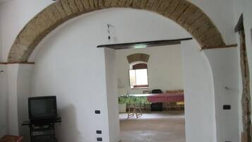 Un interno con un arco in pietra che conduce a una zona pranzo con tavolo e sedie.