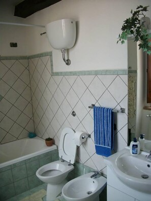 A bathroom with a bathtub, two toilets, a sink, and a mirror. - Il Casale B&B (Sant'Agata de'Goti)