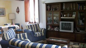 Un soggiorno con divano, televisione e un mobile in legno con ante in vetro.
