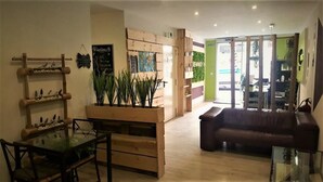 A modern interior with a wooden dining table, a brown leather couch, and a green wall with a sign. - Easy Sants by Bossh Hotels (Barcelona)