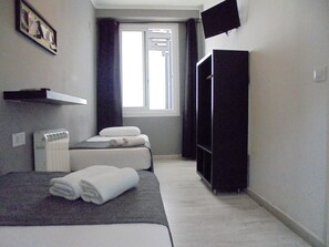 A hotel room with a bed, a heater, a TV, and a window with curtains. - Easy Sants by Bossh Hotels (Barcelona)
