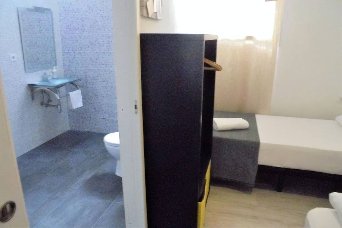 A small bathroom with a toilet, sink, and a bed.