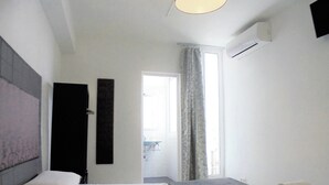 A modern hotel room with a large bed, a bedside table, a flat-screen TV, and a view of the outdoors through a window. - Easy Sants by Bossh Hotels (Barcelona)