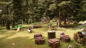 A park with a playground, wooden benches, and potted plants. - Hotel Rennsteig (Steinbach am Wald)