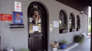 A hotel entrance with a dark wooden door, multiple windows, and potted plants. Signs indicate hotel recommendations and awards. - Hotel Rennsteig (Steinbach am Wald)