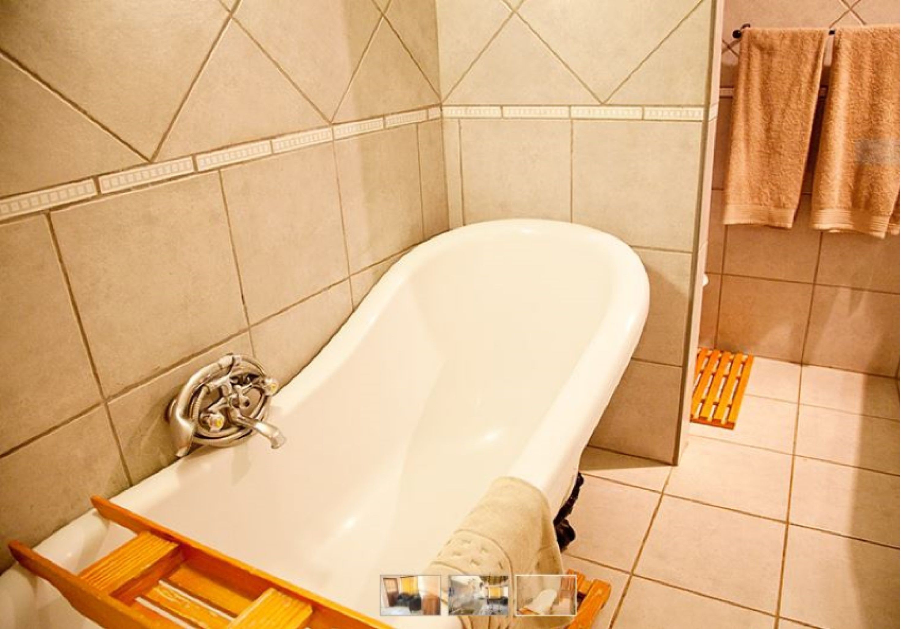 Un baño con bañera, un estante de madera y un perchero con toallas.