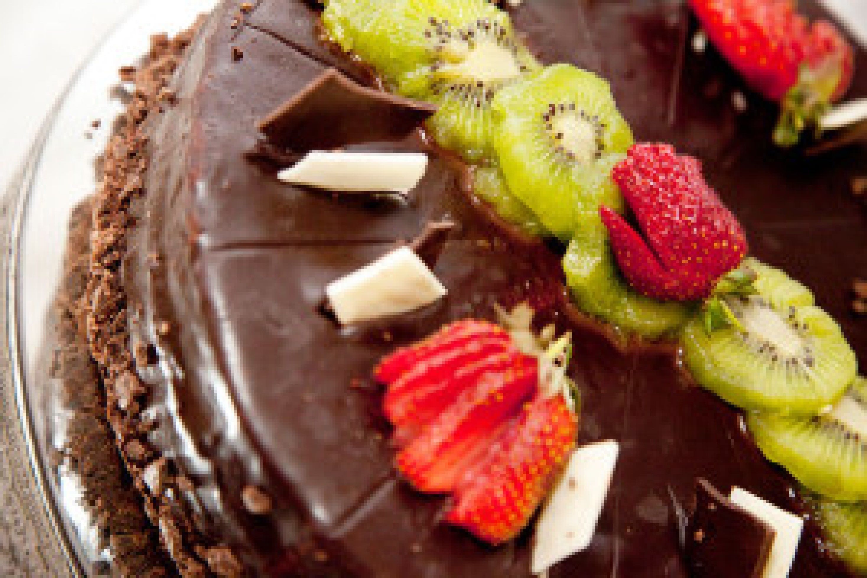 A chocolate dessert with sliced strawberries and kiwi on top.