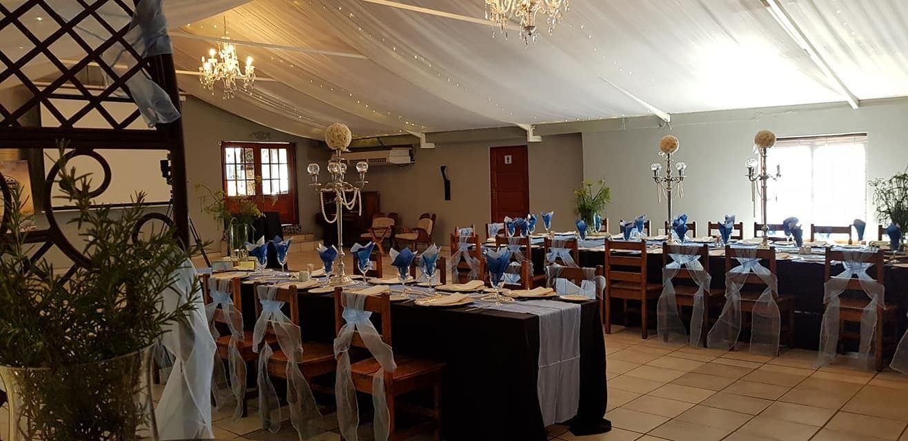 Une salle de banquet où les tables sont dressées pour un événement formel, agrémentée de lustres et de décorations florales bleues.