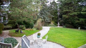 Une terrasse avec des meubles d’extérieur, un chemin de gravier et une pelouse bien entretenue.